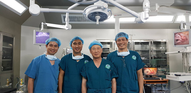 Ê-kíp phẫu thuật mặc áo xanh chụp ảnh trong phòng mổ