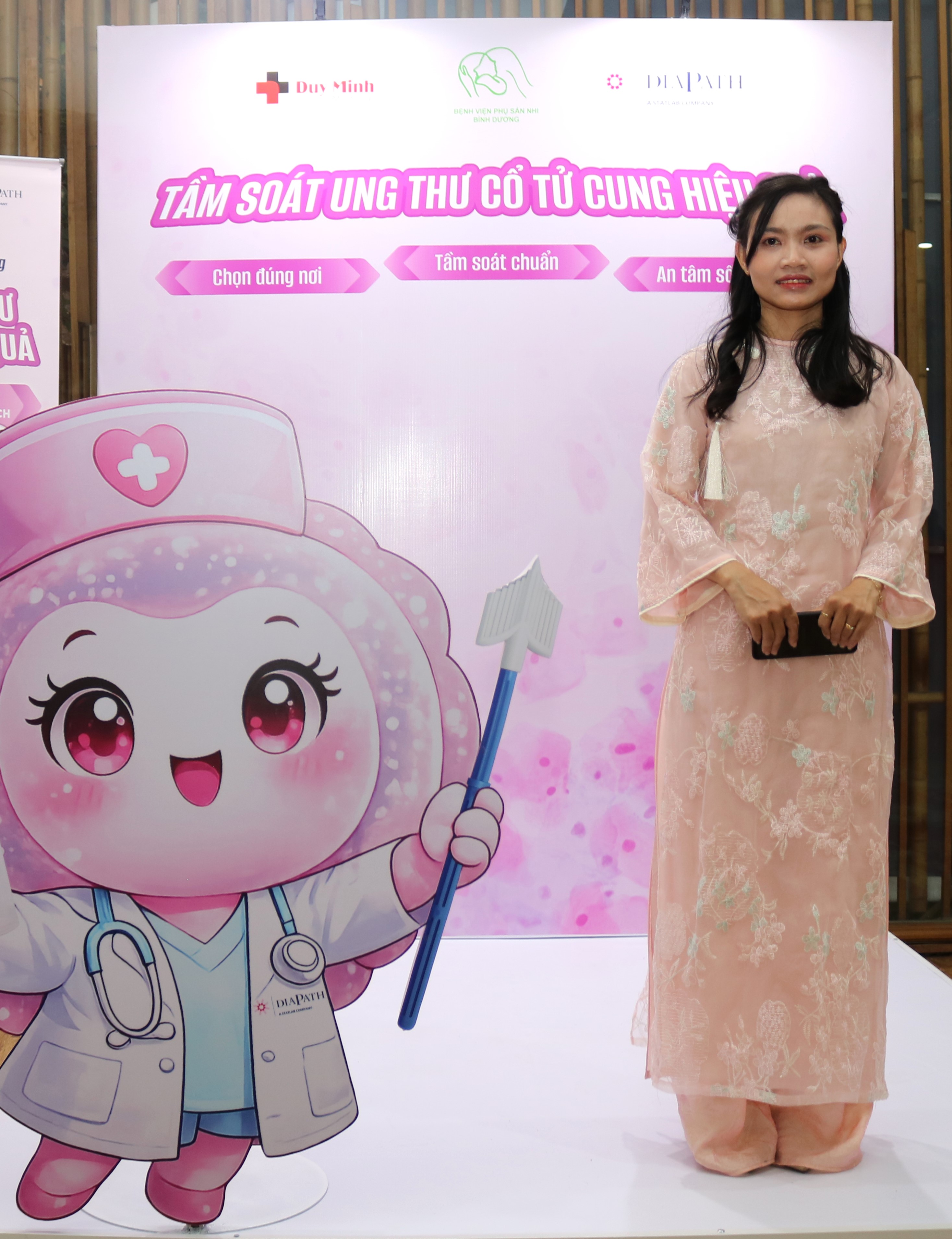Đại biểu mặc áo dài hồng chụp ảnh tại gian tầm soát ung thư cổ tử cung của Duy Minh
