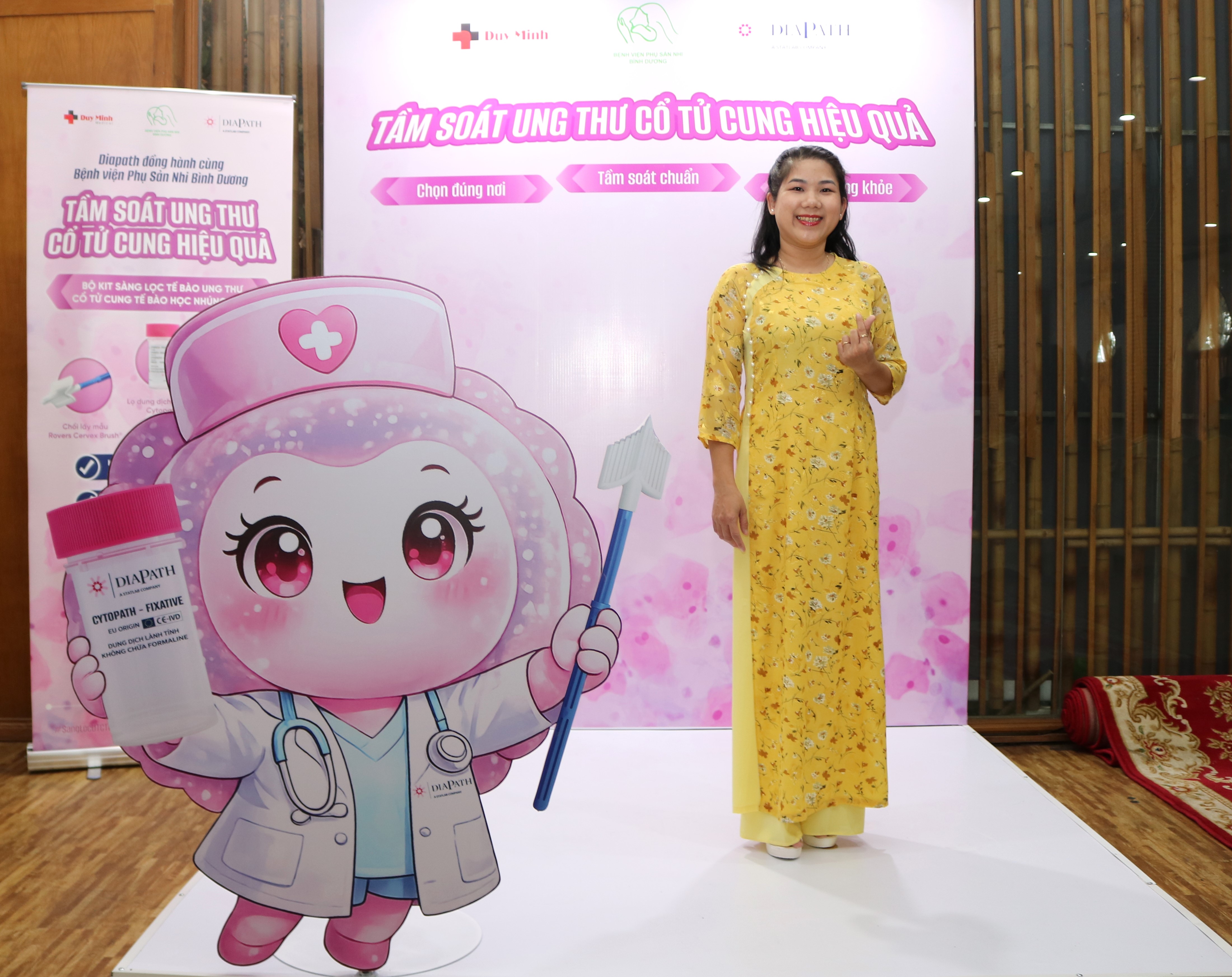 Đại biểu mặc áo dài vàng chụp ảnh tại gian tầm soát ung thư cổ tử cung của Duy Minh