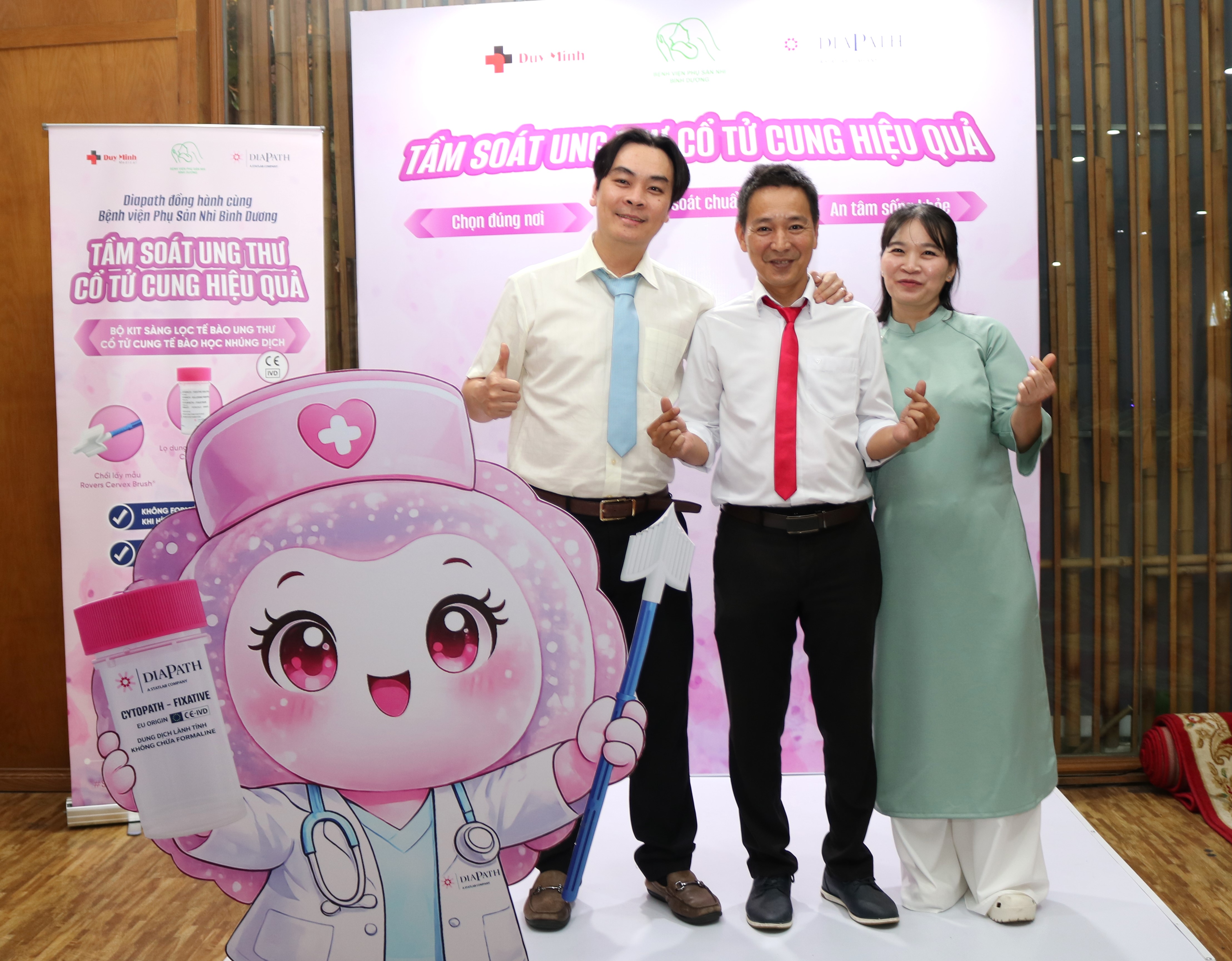 Ba đại biểu chụp ảnh cạnh mô hình linh vật tại gian tầm soát ung thư cổ tử cung