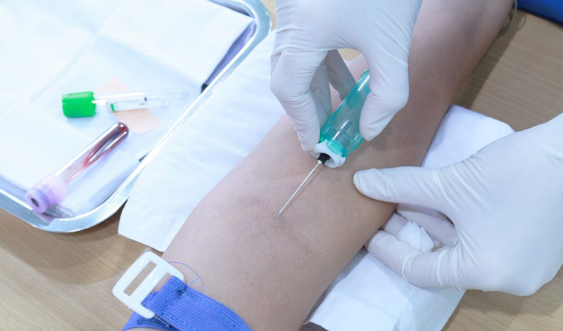 Nhân viên y tế đâm kim lấy máu chân không ở tĩnh mạch cẳng tay